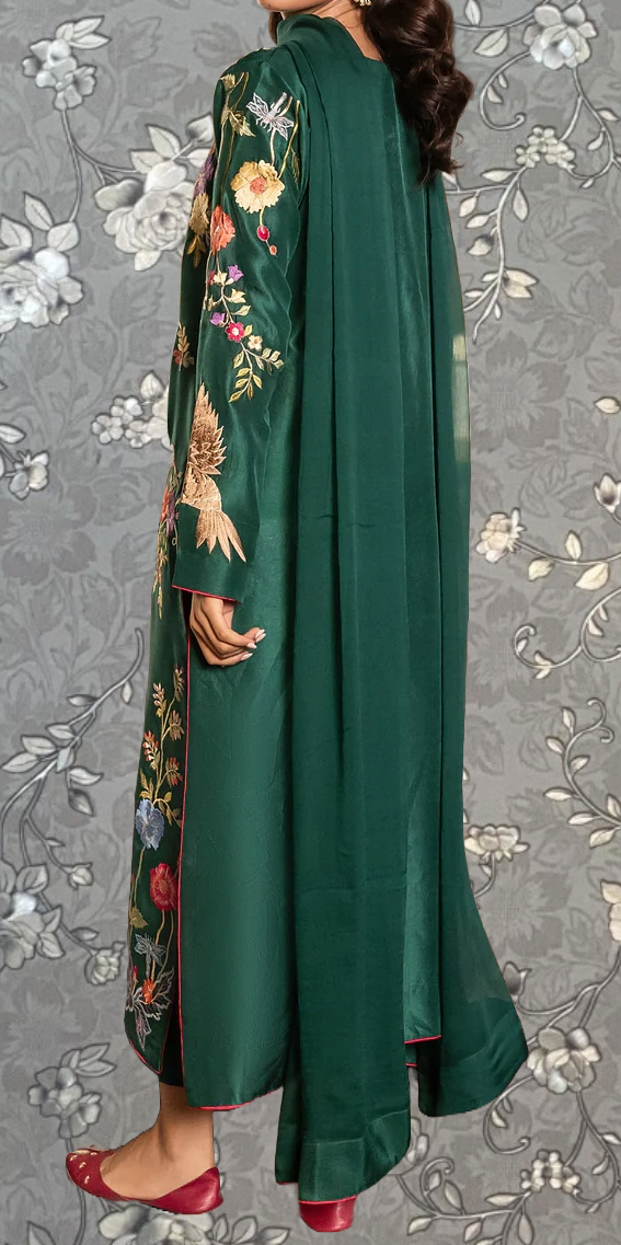 A person wearing a long green dress with floral embroidery and a matching green shawl.