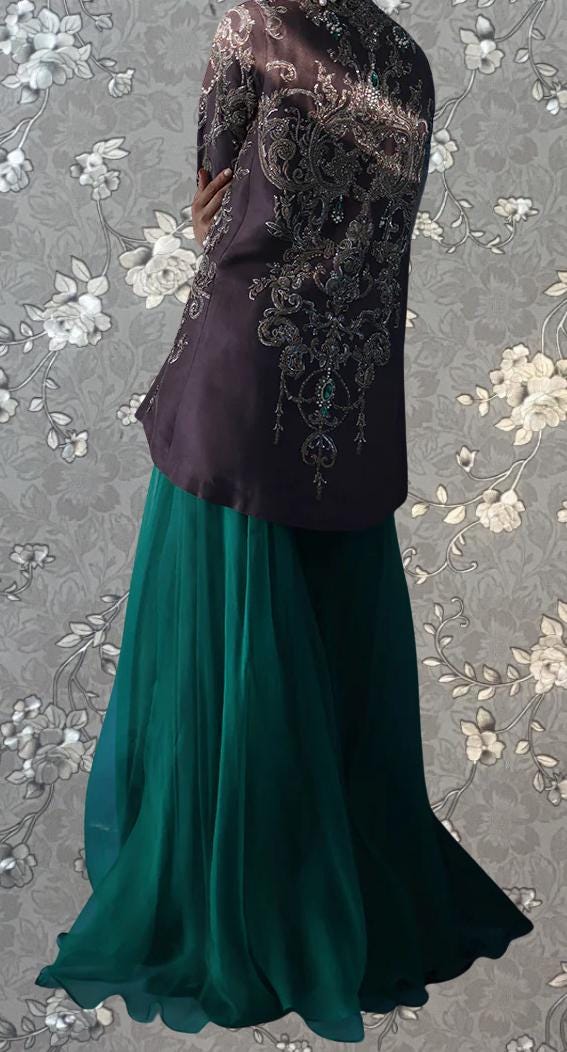 a person wearing a purple jacket with intricate embroidery and a long, flowing green skirt.