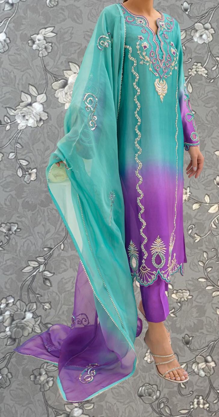 A woman wearing a long, colorful dress with intricate embroidery and patterns in shades of blue, purple, and green.