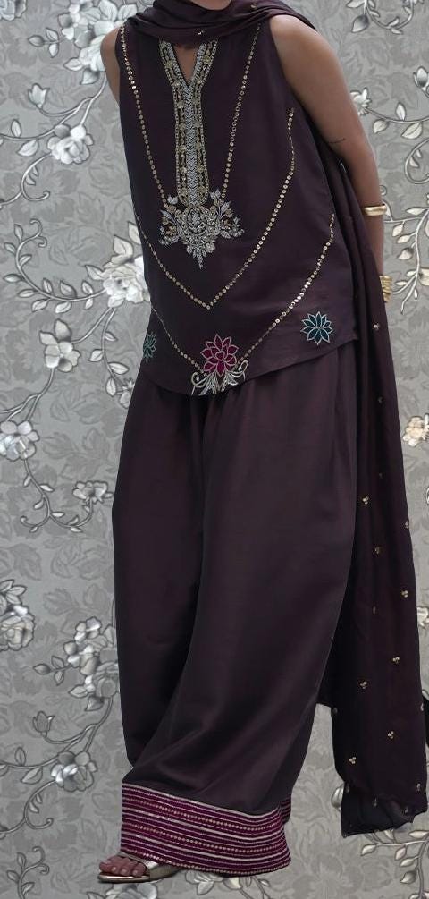 A person wearing a purple dress with intricate embroidery and a matching purple shawl.