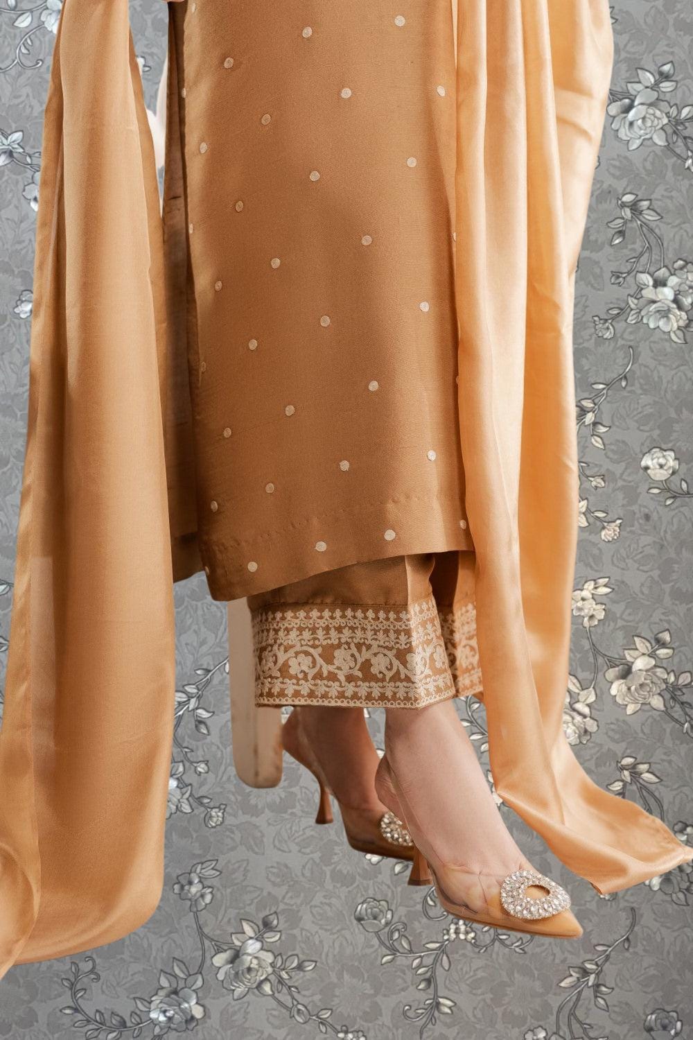 A close-up view of a person wearing a gold-colored dress with a floral pattern, paired with high-heeled shoes.