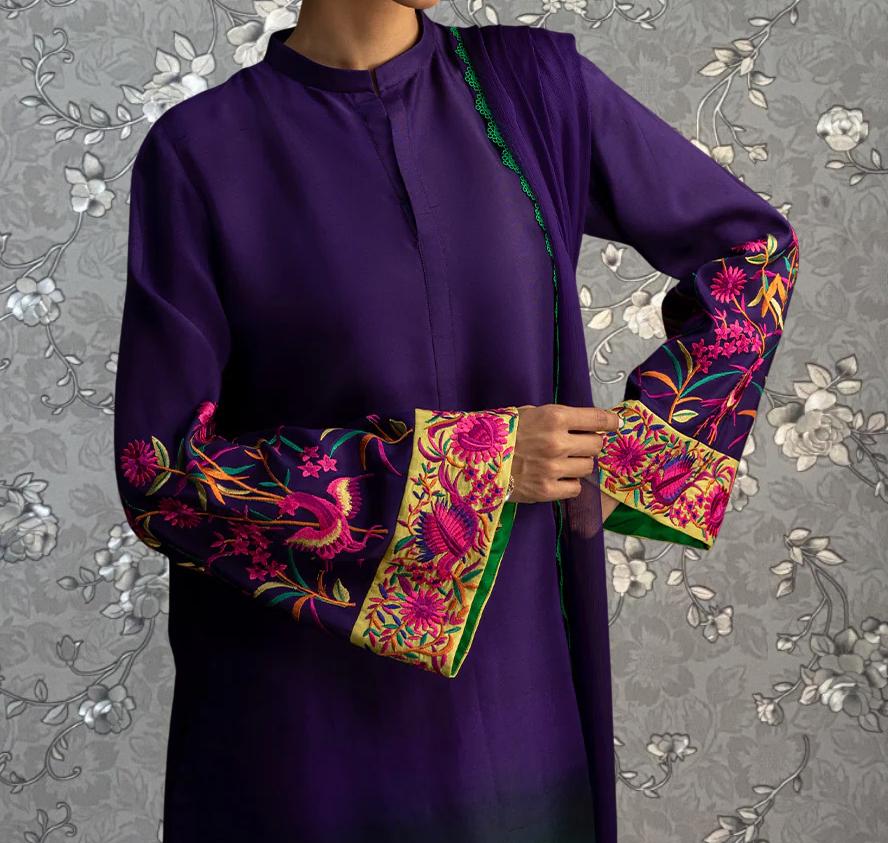 A person wearing a purple dress with colorful floral embroidery on the sleeves and collar.