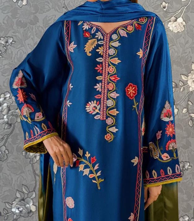 A close-up of a person wearing a blue dress with intricate embroidered patterns and designs.