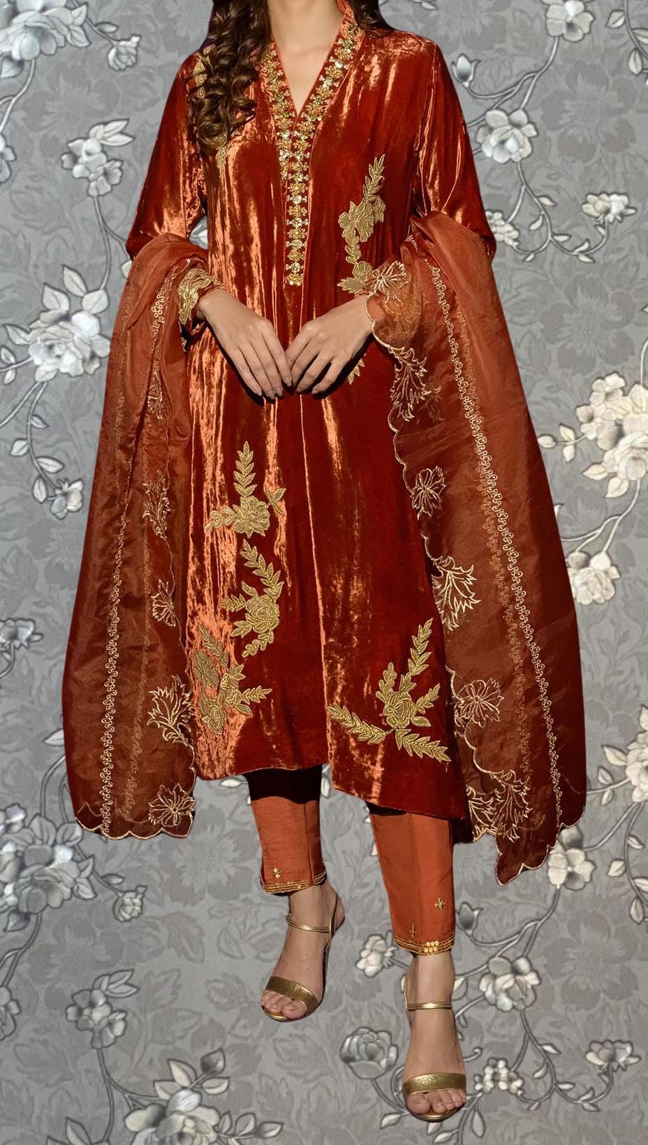 A woman wearing a red velvet dress with gold embroidery and a matching red shawl.