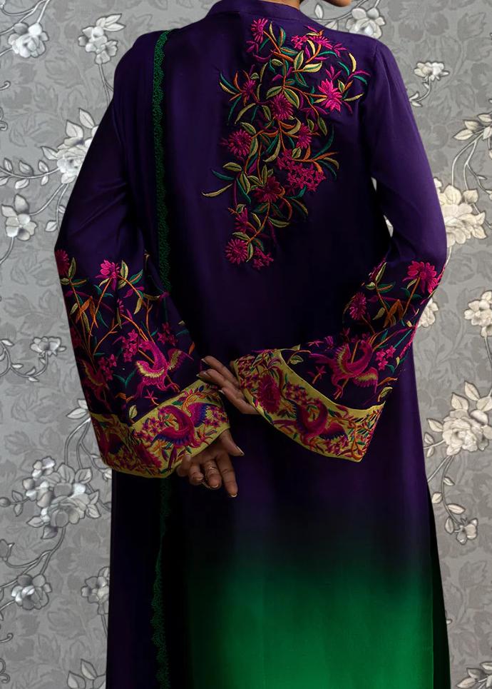 a person wearing a long purple dress with intricate floral embroidery on the back. The dress has long sleeves and a green and purple gradient effect. The person is standing against a gray floral background.