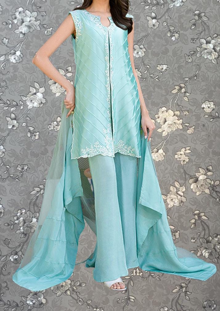 A woman wearing a turquoise dress with a long train and floral pattern on the background.