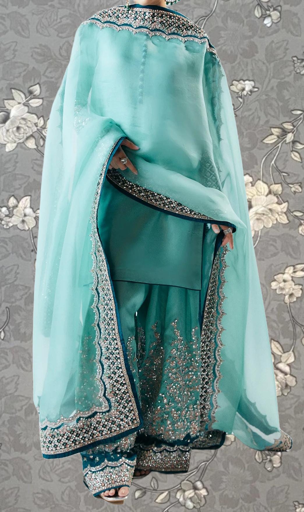 A turquoise and white traditional Indian outfit with intricate embroidery and patterns.