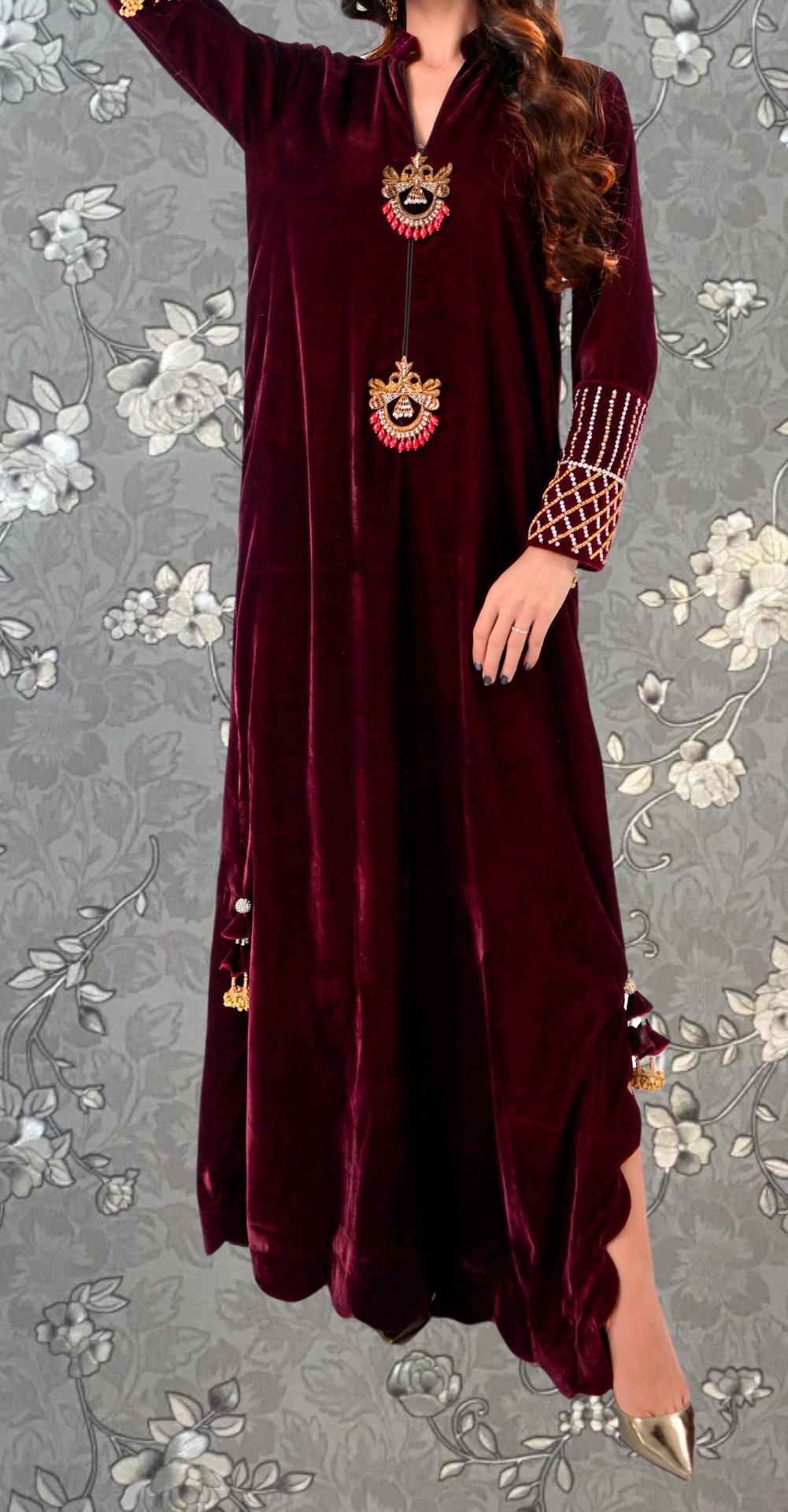 A woman wearing a long, burgundy velvet dress with intricate embroidery and tassels on the sleeves.