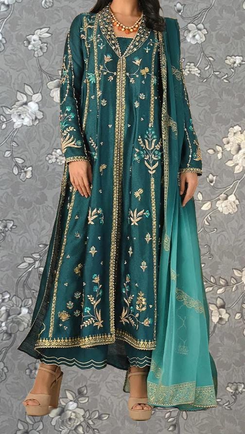 A woman wearing a long, green and gold embroidered dress with a matching green shawl draped over her shoulders.