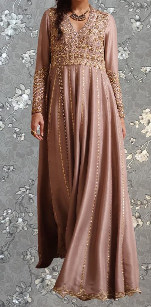 A woman wearing a long, pink dress with gold embroidery and a high neckline.