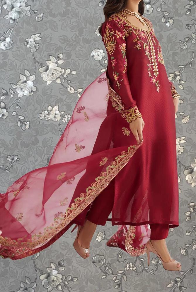A woman wearing a long red dress with gold embroidery and a flowing pink shawl.
