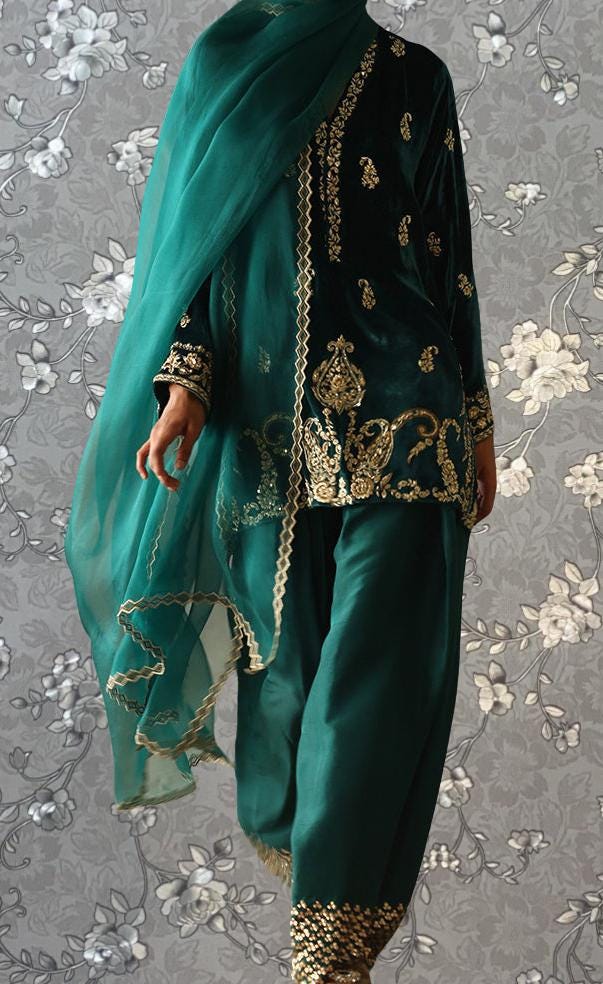 A person wearing a green and gold outfit with intricate embroidery and a matching green shawl.