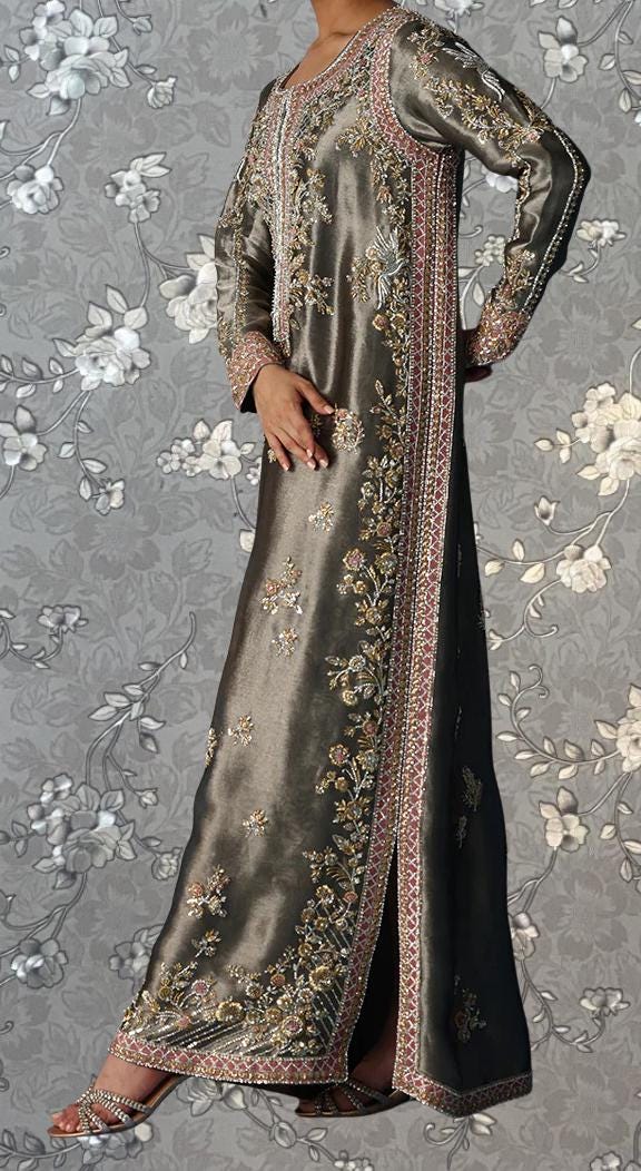 A person wearing an ornate, long gray dress with intricate embroidery and floral patterns.