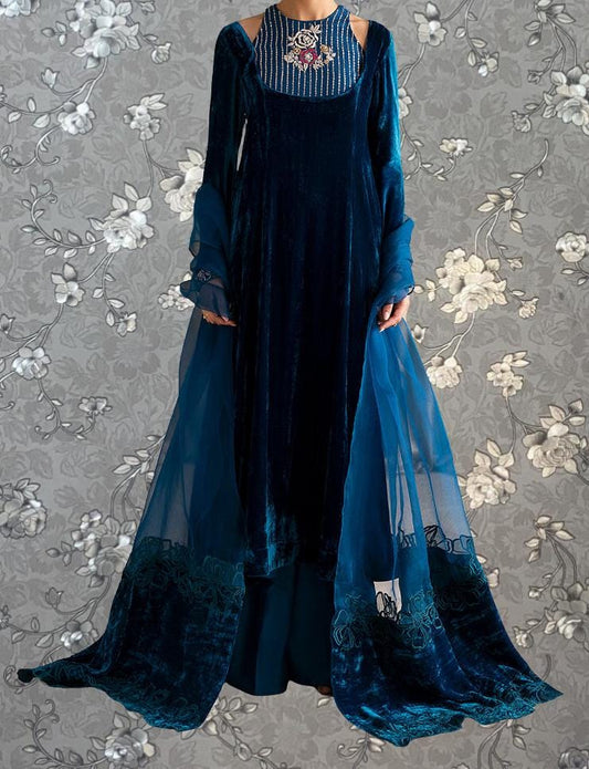 A long, blue velvet dress with a high neckline and long sleeves, featuring a sheer blue cape draped over the back.