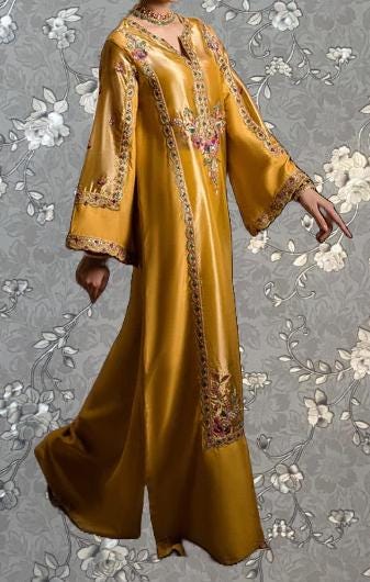 A gold-colored dress with intricate embroidery and floral patterns, featuring long sleeves and a flowing silhouette.