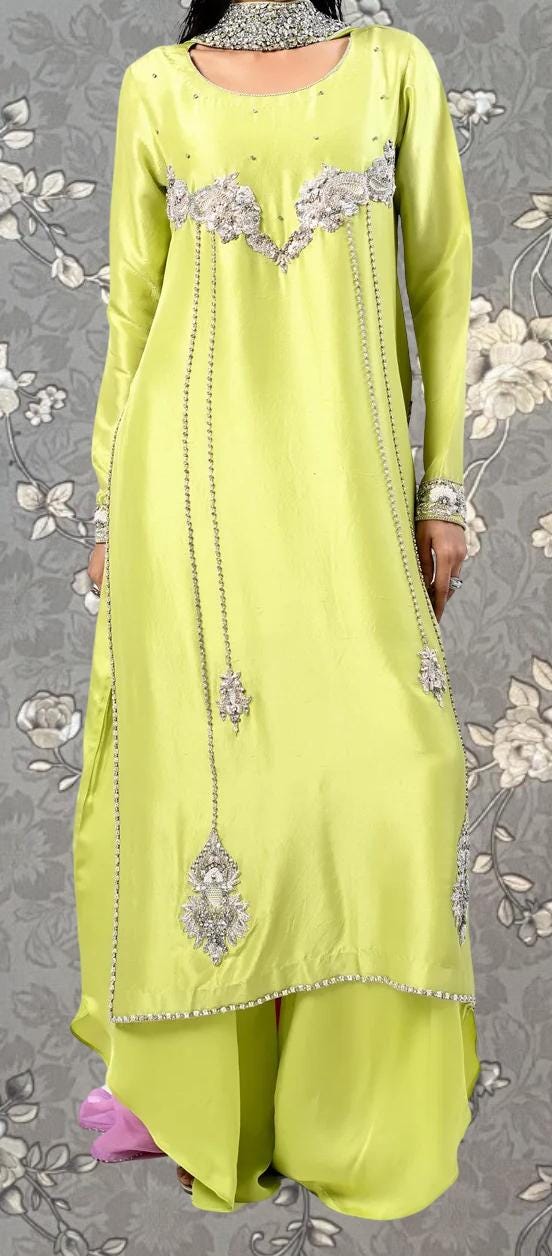 A woman wearing a bright yellow dress with intricate silver embroidery and dangling chains.