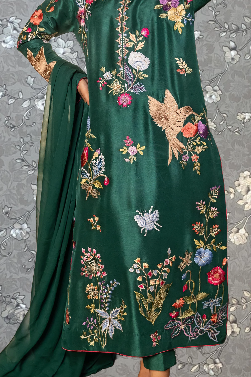 a woman wearing a green dress with intricate floral embroidery.