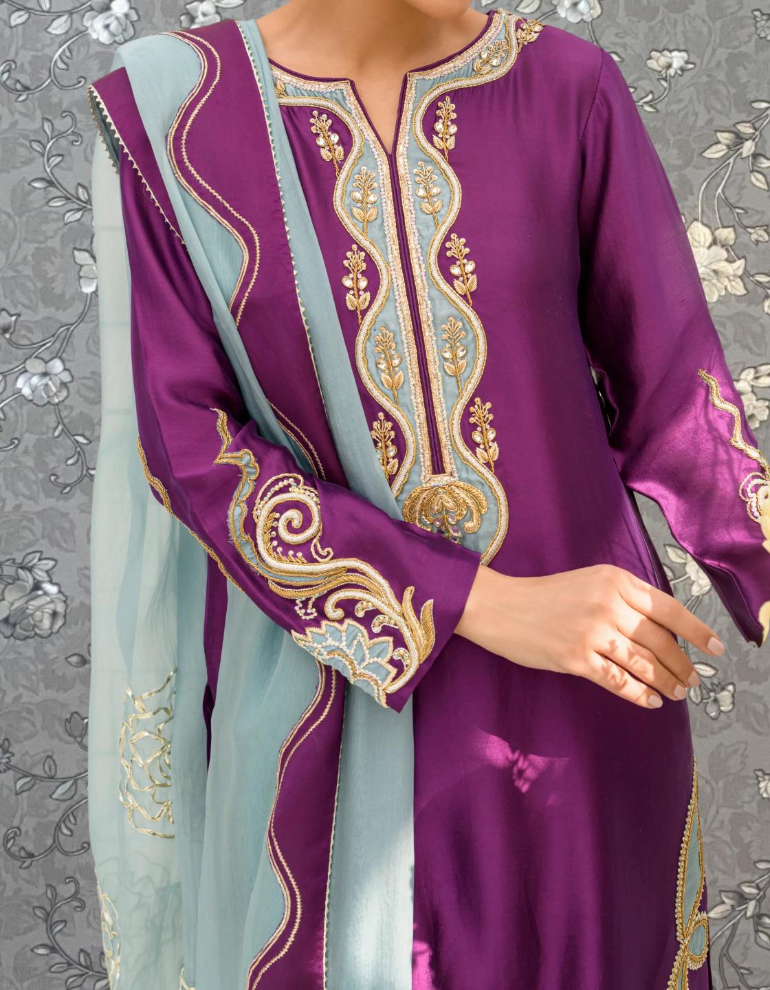 A close-up of a person wearing a purple and blue dress with intricate embroidered patterns.