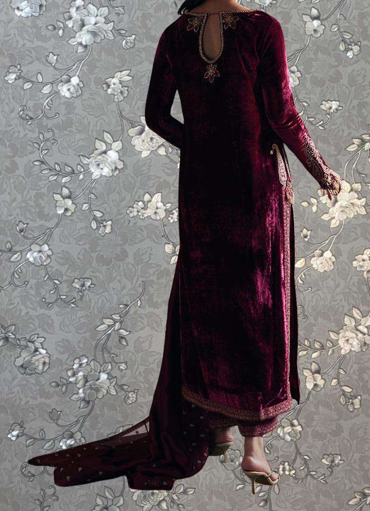 A person wearing a long, burgundy velvet dress with a floral pattern on the background.