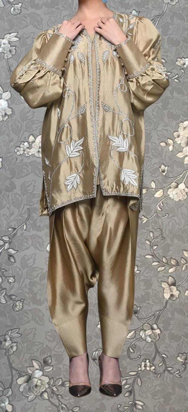 A person wearing a gold-colored, embroidered robe with puffed sleeves and a floral pattern.