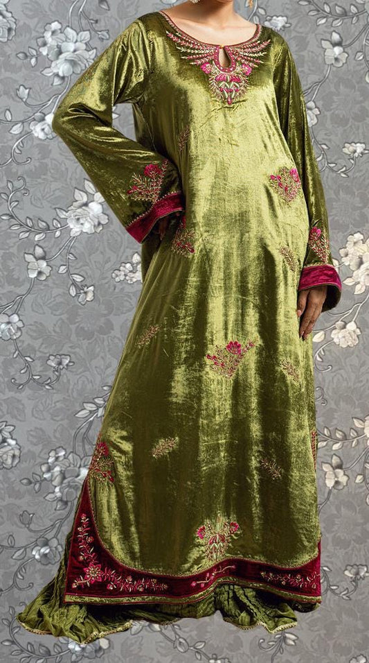 A woman wearing a long, green dress with red embroidered details on the sleeves and hem.