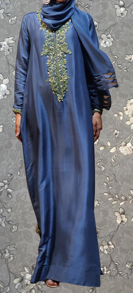 A person wearing a long, blue dress with intricate embroidered patterns on the neckline and sleeves.