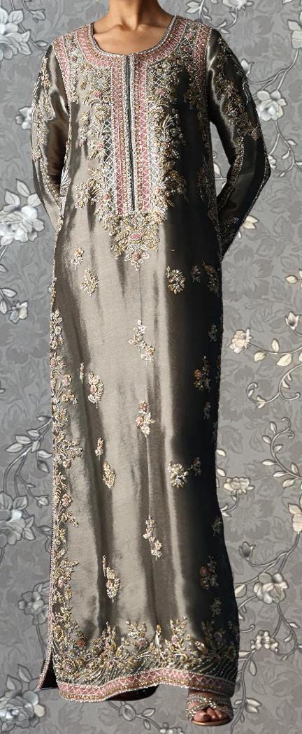 a long, gray dress with intricate embroidery and floral patterns. The dress has a high neckline and long sleeves, giving it a formal and elegant appearance. The background is a gray floral pattern, which complements the overall design of the dress.