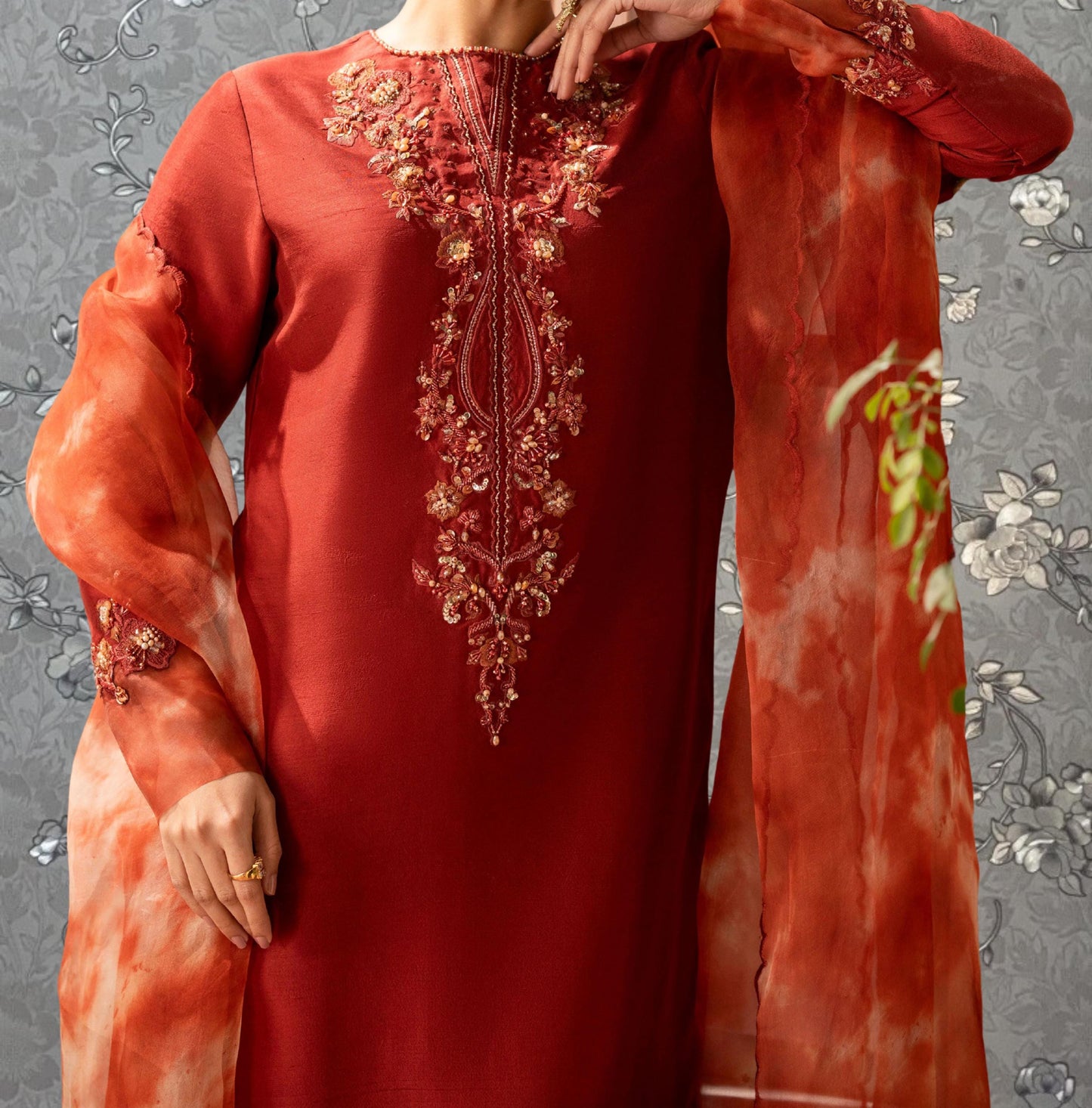 A person wearing a red dress with intricate embroidery and a matching red shawl.