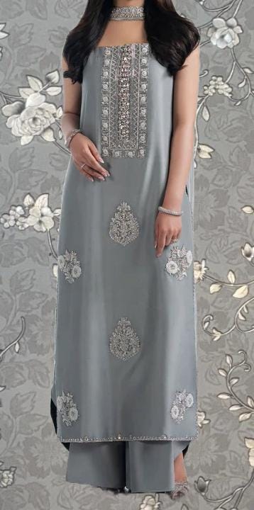 A woman wearing a gray dress with intricate embroidery and floral designs.