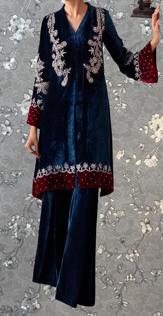 A person wearing a long, blue velvet dress with red trim and intricate embroidered designs.