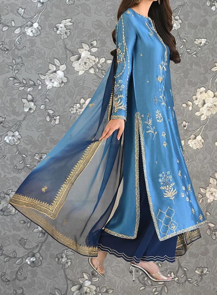 A woman wearing a long, blue dress with intricate gold embroidery and a flowing, blue and gold shawl.