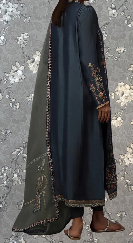 A person wearing a long, dark blue dress with intricate embroidery and a matching shawl.