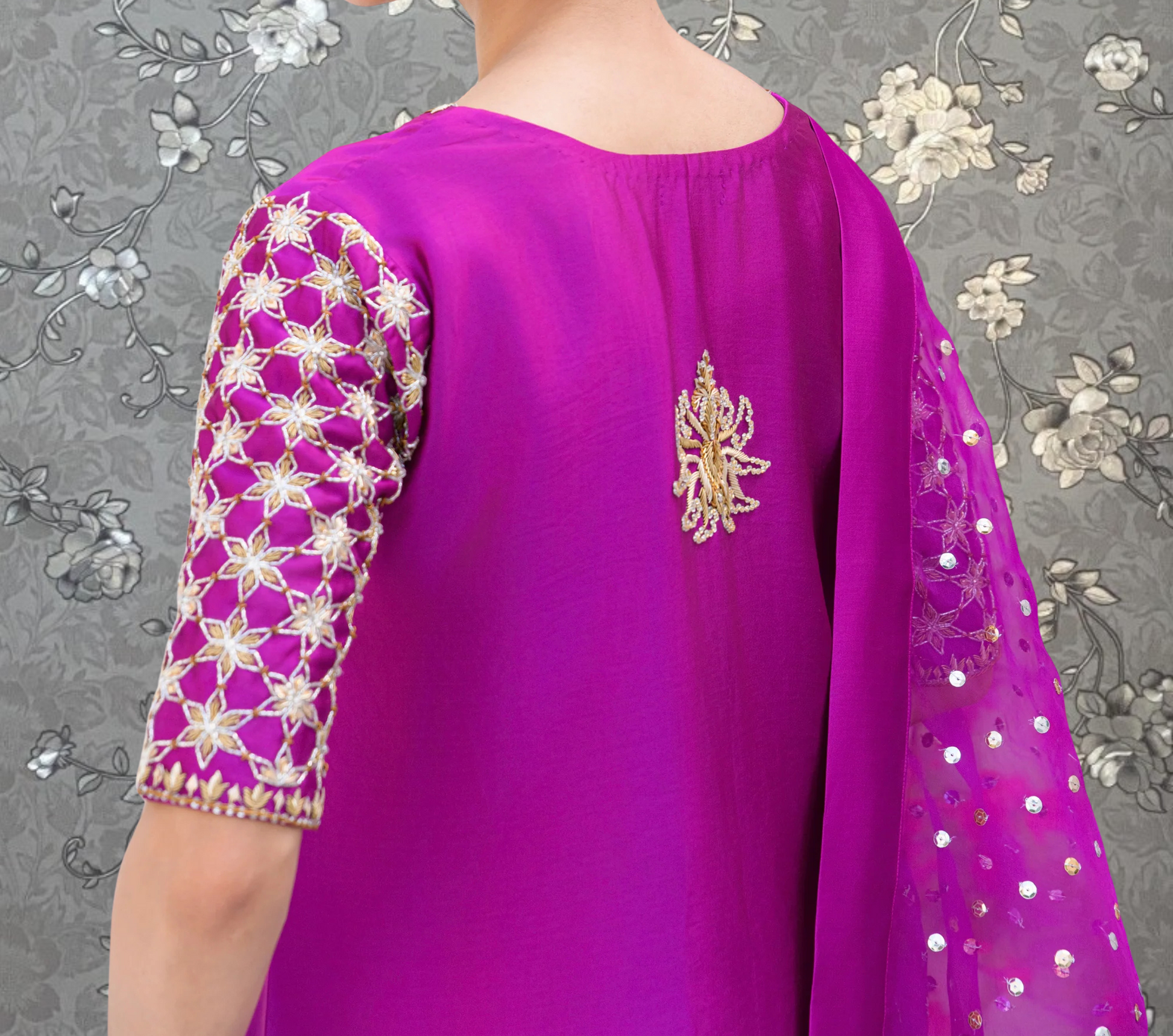 A close-up view of a person wearing a vibrant purple dress with intricate embroidered patterns on the sleeves and back.