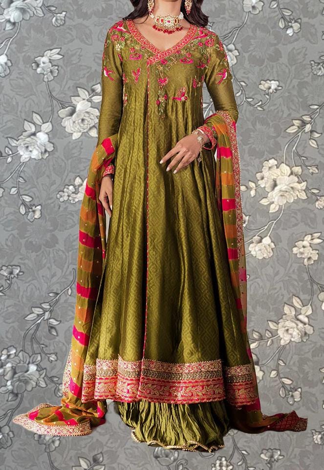 A woman wearing a long, green dress with intricate embroidery and a matching shawl.