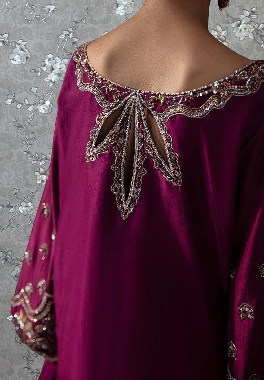 A close-up view of a person wearing a vibrant purple dress with intricate embroidery and embellishments on the back.