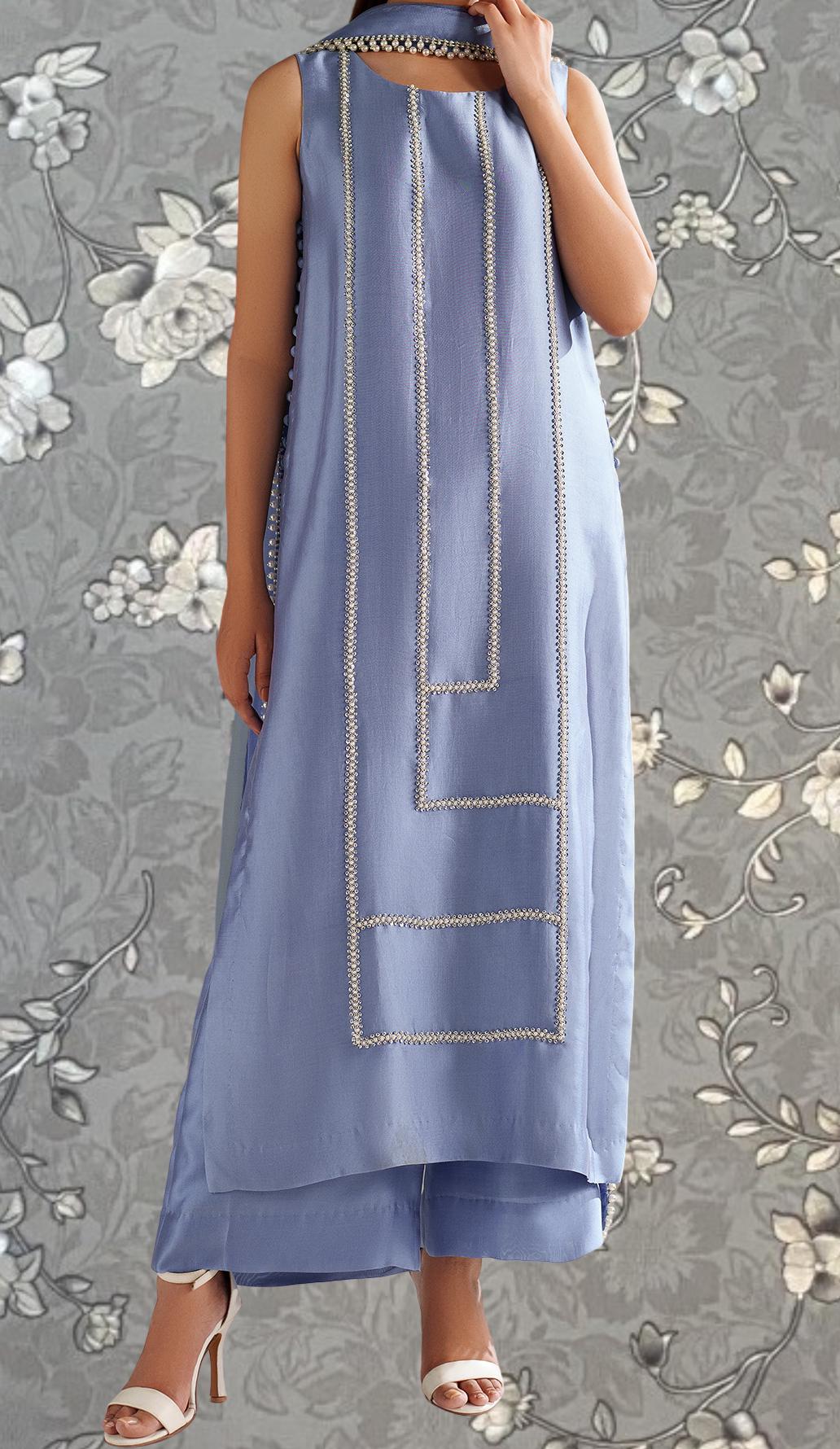 A woman wearing a long, sleeveless blue dress with a geometric pattern on the front.