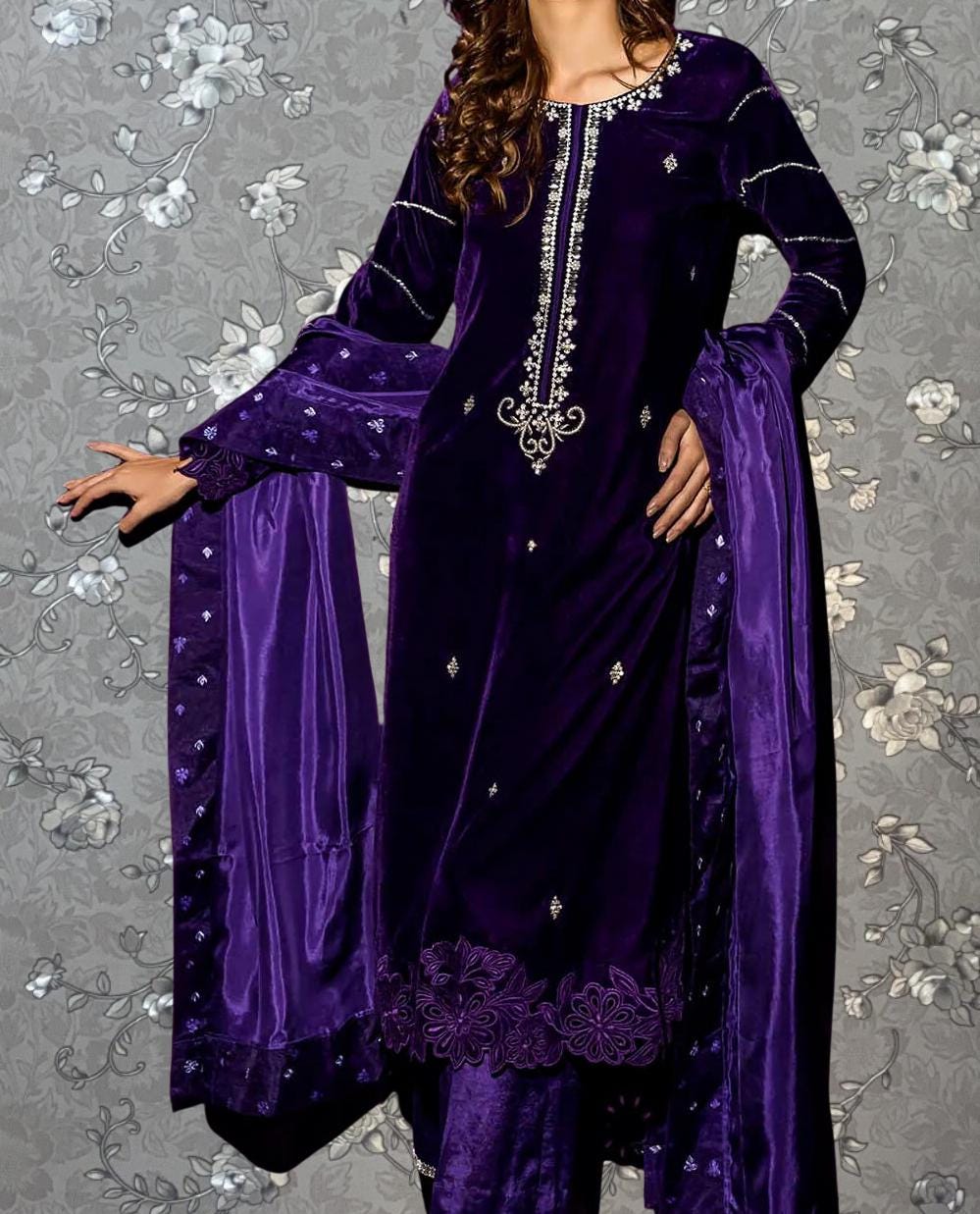 A woman wearing a purple velvet dress with intricate embroidery and a matching purple shawl.
