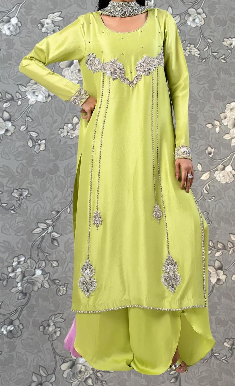 A woman wearing a bright yellow dress with intricate silver embroidery and dangling embellishments.