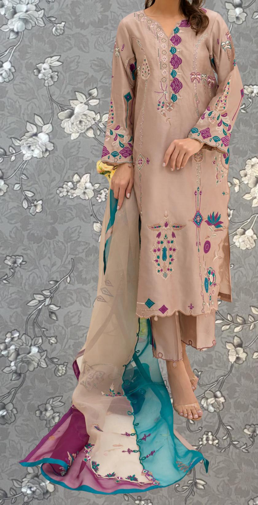 A woman wearing a beige dress with intricate embroidered designs, standing against a gray floral background.