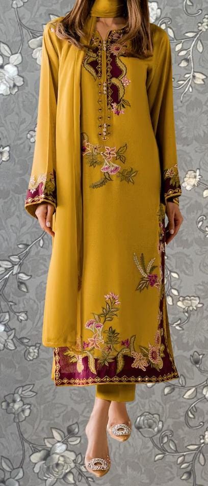 A woman wearing a long, yellow dress with intricate floral embroidery on the front and back.