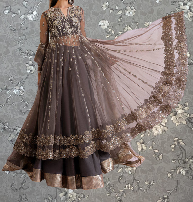 A woman wearing an ornate, long dress with intricate embroidery and a flowing skirt, posing against a floral background.