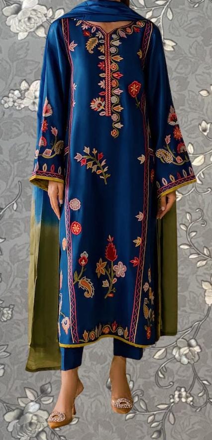 A woman wearing a blue dress with intricate embroidered designs on it.