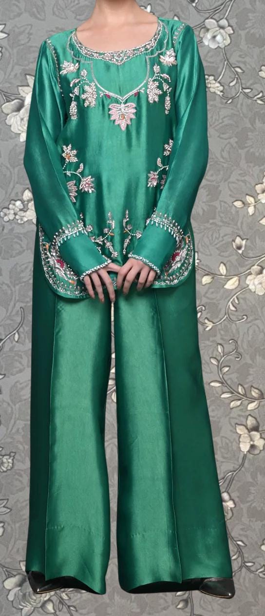 A person wearing a green dress with intricate embroidery and floral patterns.