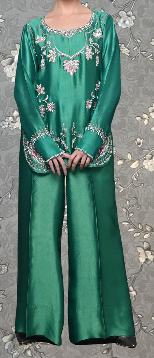 A person wearing a green dress with intricate embroidery and floral patterns.