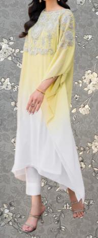 A woman wearing a yellow and white dress with intricate embroidery, standing against a gray floral background.