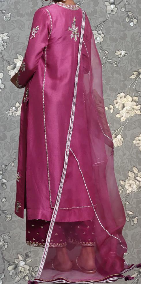 A person wearing a long pink dress with a sheer white scarf draped over the back.