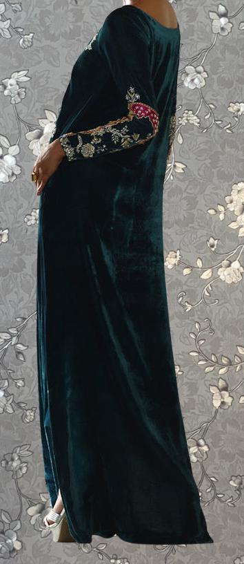 A person wearing a long, dark green velvet dress with intricate embroidered patterns on the sleeves and back.