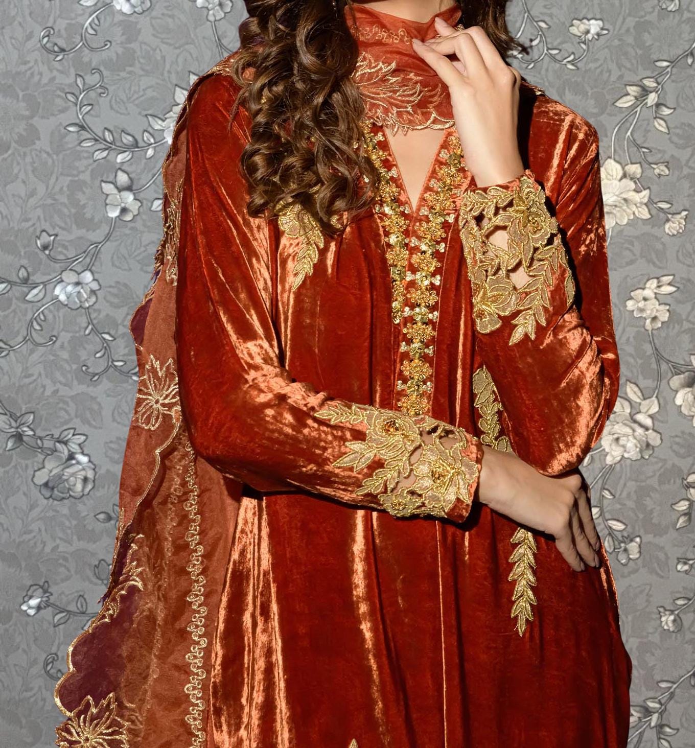 A woman wearing a vibrant red velvet dress with gold embroidery and a matching red shawl.