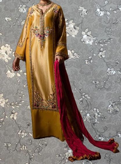 a gold and red dress with intricate embroidery, standing against a gray floral background.