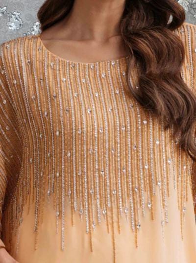 A close-up view of a woman's neck and chest area wearing a peach-colored dress with a beaded or sequined design.